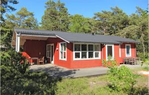 a red and white cabin with a table in front of it at 3 Bedroom Nice Home In Aakirkeby in Vester Sømarken