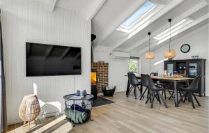 Un comedor con una mesa y un televisor en la pared. en Cozy Home In Hvide Sande With Sauna, en Bjerregård