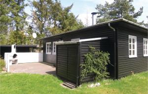 een zwart gebouw met een garage in een tuin bij Sbo in Bøtø By