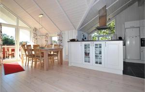 una cucina e una sala da pranzo con armadi bianchi e tavolo di Bim a Fanø