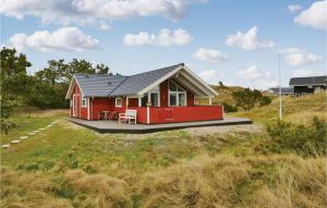 a red house with a black roof in a field at Bim in Fanø