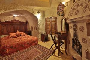 a bedroom with a bed and a desk in a stone room at Travel Inn Cave Hotel in Göreme