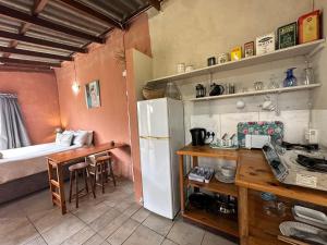 uma cozinha com um frigorífico, uma mesa e uma cama em BlueCottage or Seaview Cottage at Coram Deo Lodge self catering em Coffee Bay