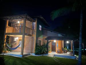 una casa con una hamaca en el patio por la noche en Residencial Alto do Arraial, en Arraial d'Ajuda