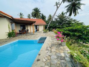 a villa with a swimming pool in front of a house at Blue Beach Villa - Nilwella in Matara
