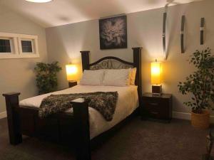ein Schlafzimmer mit einem Bett mit zwei Lampen und zwei Pflanzen in der Unterkunft Cheerful and beautiful 3 bedroom home close lake in Edmonton