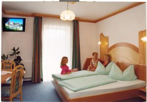 Pension Drei-Mäderl-Haus في Unterlamm: ثلاث بنات جالسات على سرير في غرفة الفندق