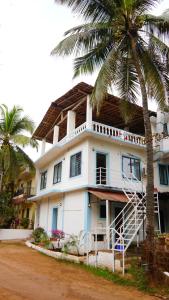 een wit huis met een palmboom ervoor bij Iksa in Mandrem