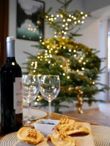 a bottle of wine and glasses on a table with a christmas tree at Apartamenty Pod Hutą in Węgierska Górka