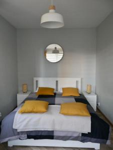 ein Schlafzimmer mit einem Bett mit gelben Kissen und einem Spiegel in der Unterkunft Apartamenty Pod Hutą in Węgierska Górka