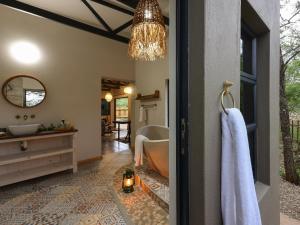 a bathroom with a tub and a sink and a mirror at Grace of Africa, Kruger Couples Nature Lodge in Marloth Park