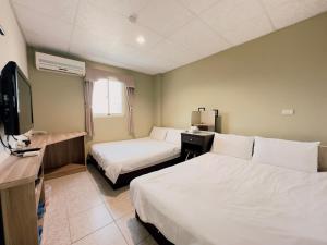 a hotel room with two beds and a flat screen tv at Jin Lu Homestay in Jincheng