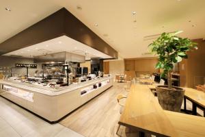 a large kitchen with tables and a counter in a restaurant at Richmond Hotel Nagoya Shinkansen-guchi in Nagoya