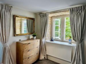 a bedroom with a dresser and two windows with curtains at Period apartment, great views, in heart of town. in Bradford on Avon