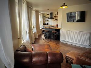 a living room with a brown leather couch and a kitchen at Period apartment, great views, in heart of town. in Bradford on Avon