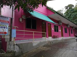 ein rosafarbenes Gebäude mit einem Schild davor in der Unterkunft Baan Nakarin Guest House บ้านนครินทร์ in Patong Beach