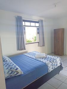 1 dormitorio con cama con sábanas azules y ventana en Itapuã Corais Hostel e Pousada, en Salvador