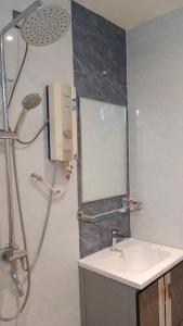a bathroom with a shower with a sink and a mirror at Sumai Hotel Apartment in Kuala Terengganu