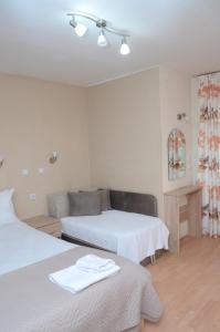 een witte kamer met 2 bedden en een bank bij Villa Konzuli in Bitola