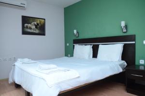 a bedroom with a large white bed with green walls at Villa Konzuli in Bitola