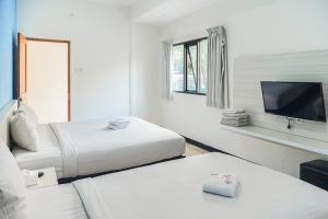 a white room with two beds and a flat screen tv at TwoSpaces Living at Panorama Villas in Batu
