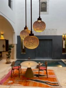 um quarto com uma mesa, cadeiras e luzes em Riad Dar Massai em Marrakech