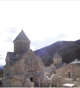 an old stone church with a mountain in the background at Guest House in Aghxstef in Haghartsin