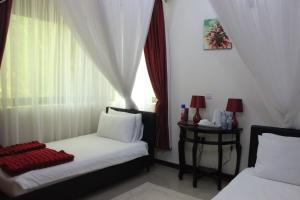 1 Schlafzimmer mit 2 Betten und einem Fenster mit Vorhängen in der Unterkunft Signature Hotel Apartments in Jinja