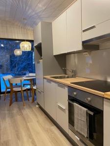 a kitchen with white cabinets and a dining table at Tammikon Tupa in Tuusula