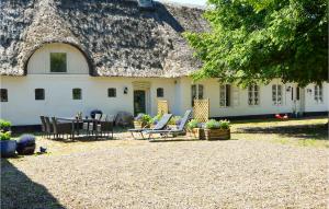 a house with a thatched roof with chairs and a table at Drosselgrden in Branderup