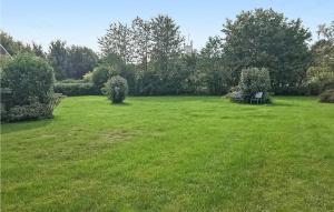 a green field with a table and chairs in it at Cozy Home In stermarie With Kitchen in Østermarie