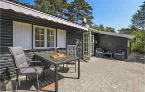 a patio with a table and chairs in front of a house at Mosehytten in Neksø