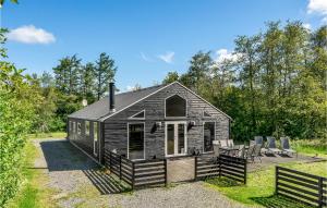a black cabin with chairs and tables in a field at Nice Home In Oksbl With Sauna in Ovtrup