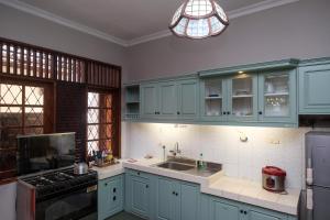 a kitchen with blue cabinets and a sink and a stove at SAREH VILLA by The Lavana in Semarang