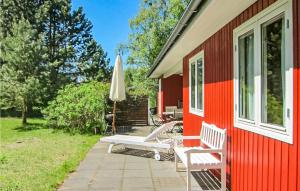 ein rotes Haus mit zwei Stühlen und einem Regenschirm in der Unterkunft Awesome Home In Aakirkeby With Kitchen in Vester Sømarken + 25 Fotos
