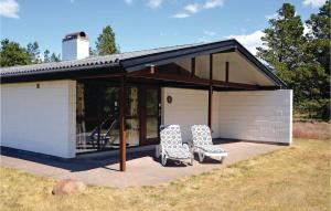 2 sedie sedute su un patio di fronte a un edificio di Holiday Home Fyrrekrogen Nørre Nebel Iii a Lønne Hede