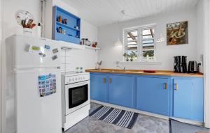 una cucina con armadi blu e frigorifero bianco di Holiday Home Tranebærvej Oksbøl Iii a Vejers Strand Altre 11 foto