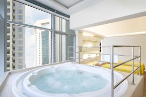 a large bath tub in a room with windows at Qabila Westbay Hotel by Marriott in Doha