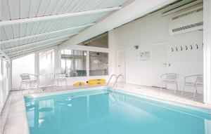 a swimming pool in a house with chairs in it at Cozy Home In Hjrring With House Sea View in Lønstrup