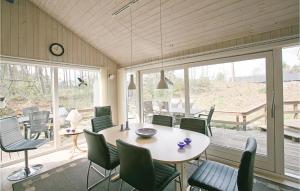 a dining room with a table and chairs and windows at 4 Bedroom Lovely Home In Nex in Snogebæk