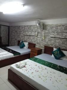 a bedroom with two beds and a brick wall at White River guesthouse in Phnom Penh