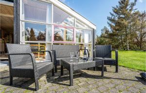 a patio with three chairs and a table with wine glasses at Holiday Home Gøgeurtvej Væggerløse X in Marielyst +18 photos