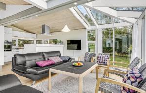 una sala de estar con un sofá de cuero negro y sillas en Cozy Home In Haarby With House Sea View en Brydegård