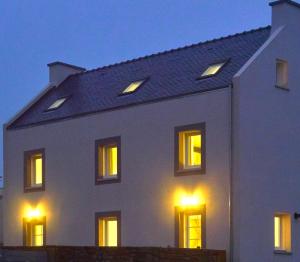 Casa blanca con luces en las ventanas en La vigie d'Héloïse, appartement de l'Aod en Lampaul