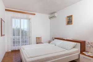 een witte slaapkamer met een bed en een raam bij Guest House Oreb in Koločep
