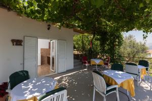 eine Terrasse mit Tischen und Stühlen unter einem Baum in der Unterkunft Guest House Oreb in Koločep