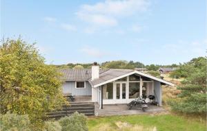 a small white house with a porch and a motorcycle on a deck at Hedebo in Fanø