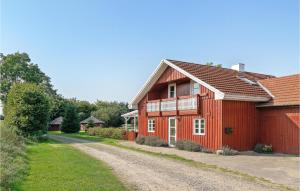 a red house on a dirt road next to a driveway at Pet Friendly Home In Christiansfeld With Sauna in Christiansfeld