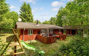 a red cabin in the woods with a playground at Pet Friendly Home In Ansager With Kitchen in Ansager