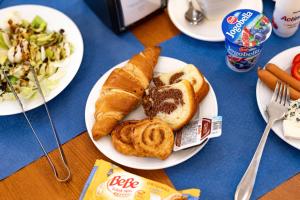 a table topped with plates of food with bread and vegetables at Hotel Belcredi in Brno